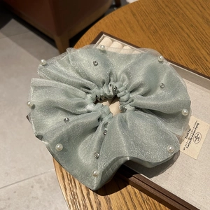 Detail of mint green mesh hair scrunchie with white pearls and sparkling rhinestones