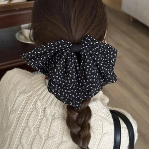 Detail view of large polka dot mesh bow hair clip styled on a low braided ponytail