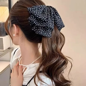 Detailed view of a black polka dot mesh bow hair clip styled on a high ponytail for women
