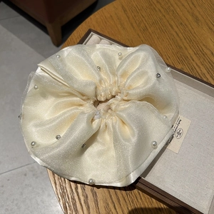 Detail of cream organza hair scrunchie with pearls and rhinestones in jewelry box