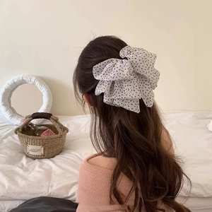 Detail showing white polka dot mesh bow hair clip on a model's ponytail for vintage styling