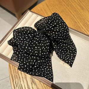 Close-up of black polka dot mesh bow hair claw clip on a white jewelry display tray