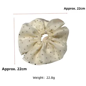 Détail d'un chouchou en tulle beige à pois de 22cm orné de perles blanches élégantes