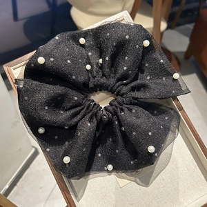 Détail d'un chouchou en organza noir orné de paillettes et de perles élégantes