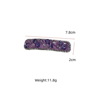 Detail view of a 7.8cm x 2cm purple crystal hair clip with small white zircon borders