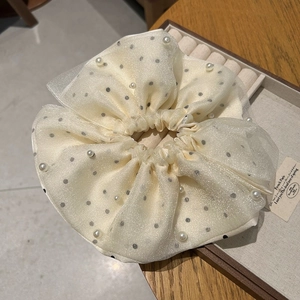 Détail d'un chouchou en tulle crème avec pois gris et perles blanches brillantes