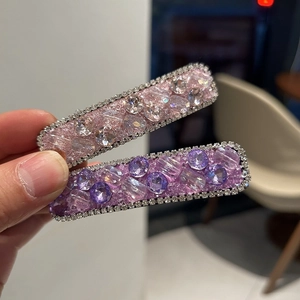 Detail view of two rectangle hair clips with pink and purple crystals and rhinestones