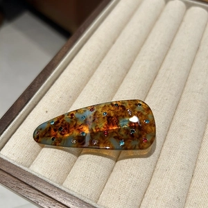 Close-up of tortoise shell hair clip with colorful rhinestones on velvet tray