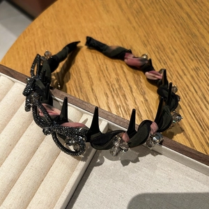 Détail d'un serre-tête noir avec nœud en cristal et rivets sur tissu texturé