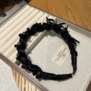 Elegant black satin headband with crystal bow and beads shown on jewelry display tray