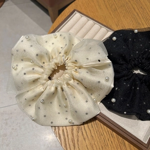 Chouchous en résille à pois avec perles blanches en crème et noir sur table en bois