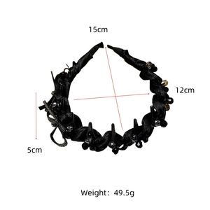 Detail of black twisted satin headband featuring faceted beads and metallic bow accent