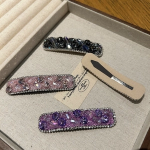 Detail of four crystal hair clips with sparkling rhinestones in pink, purple and black