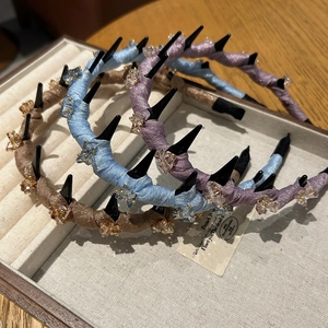 Close-up of three satin headbands in blue, purple, and beige with chic spikes and beads
