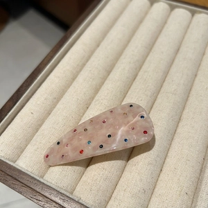 Detailed macro view of pink marble acetate hair clip with colorful inlaid rhinestones