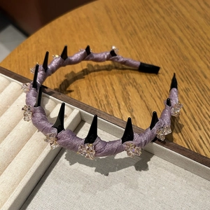 Detail of lavender satin headband with black spikes and champagne crystal clusters