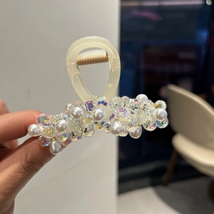 Dettaglio macro della molletta per capelli color crema con perle e cristalli lucidi