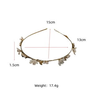 Detalle de diadema dorada con flores blancas y perlas con medida de 15cm mostrada