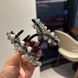 Dettaglio di un fermaglio per capelli nero decorato con perle e perline di cristallo