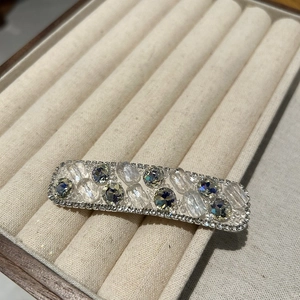 Close-up of a silver rectangular hair clip with sparkling rhinestones and clear crystals