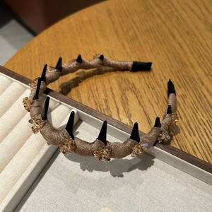 Detail of mesh headband with spikes and champagne crystals on wood and white background