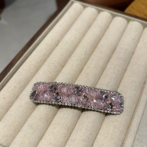 Detailed close-up of a pink crystal hair clip with shimmering rhinestones and alloy base