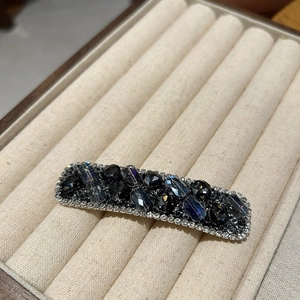 Detailed macro view of crystal hair clip with dark grey stones and silver rhinestone borders