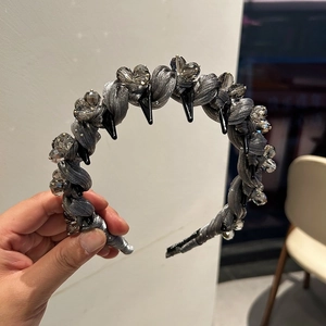 Détail d'un serre-tête en tissu gris avec perles en cristal tressées et pointes noires