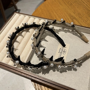 Dettaglio di cerchietti di lusso con perle bianche, cristalli fumé e punte nere decorative