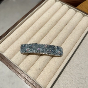 Close-up of rectangular hair clip with blue crystals and white diamond border inlay