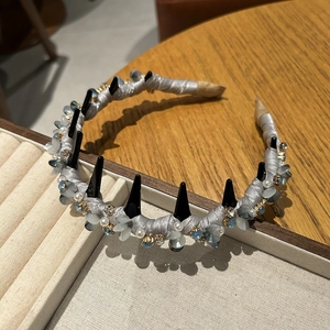 Dettaglio del cerchietto in raso grigio con borchie punk nere, perle e cristalli decorati