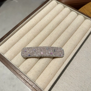Detail of a rectangular hair clip featuring pink rhinestones and white zircon borders