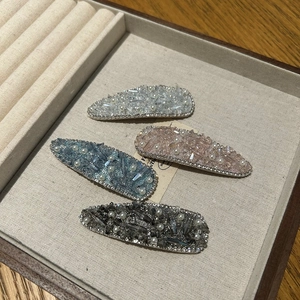 Macro shot of four colorful rhinestone hair clips with faux pearls in a luxury display box