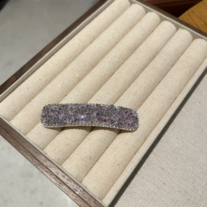 Close-up of luxury rectangular hair clip with purple and iridescent rhinestones