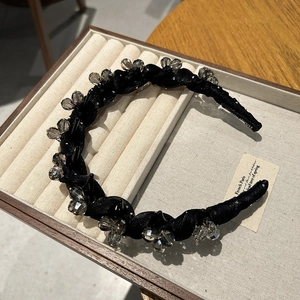 Détail d'un serre-tête en tissu noir orné de perles de cristal de style français élégant