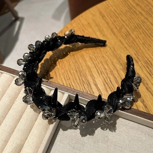 Détail d'un serre-tête noir fait main avec perles de cristal et pointes sur velours