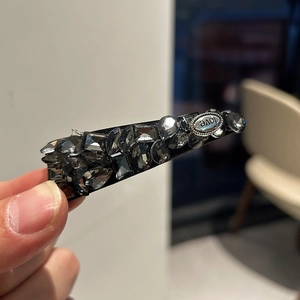 Macro detail of luxury duckbill hair clip with dark crystals and LOVE metal plate