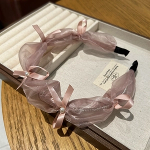 Close-up of pink organza headband with delicate ribbon bow and white pearl accents
