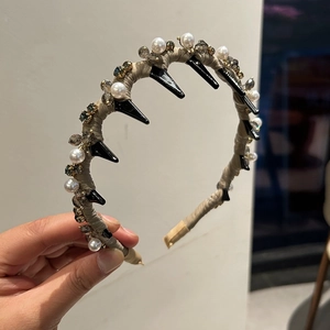 Dettaglio del cerchietto in raso kaki con denti neri, perle e cristalli grigi