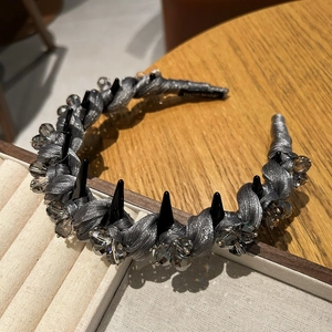 Détail du serre-tête en soie argentée avec cristaux gris et pointes gothiques noires