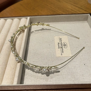 Vue détaillée d'un serre-tête floral doré avec perles blanches et strass sur velours