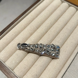 Close-up of a sparkling crystal BB hair clip with LOVE metal tag on beige velvet tray