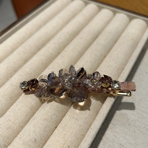 Close-up of elegant gold duckbill hair clip with brown and purple crystal beads cluster