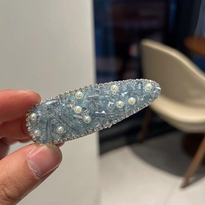 Detail of luxury teardrop hair clip with blue glitter, rhinestones and white pearls