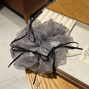 Grey tulle scrunchie with black ribbon bows displayed on a wooden jewelry tray
