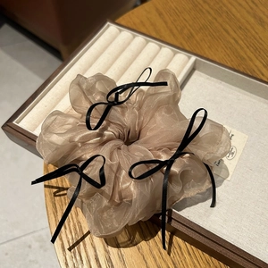 Champagne organza scrunchie with black ribbon bows displayed on a jewelry tray