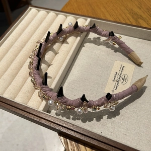 Dettaglio del cerchietto in raso lavanda con punte nere e cristalli su base elegante
