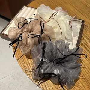 Detail of three large organza scrunchies with ribbons in white, champagne, and grey colors