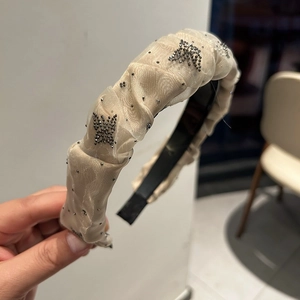 Détail d'un serre-tête en tulle beige orné de strass noirs et de motifs de papillons