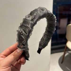Détail d'un serre-tête en tulle plissé gris argenté orné de strass brillants